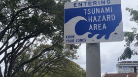 FILE - A sign indicates the border of the tsunami evacuation zone on Kalākaua Avenue on Oʻahu.