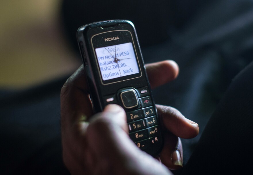 A recipient of cash aid through GiveDirectly's experiment checks his phone to confirm that the latest monthly transfer has been made.