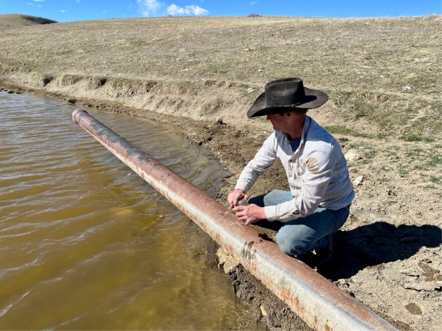 Rancher Lamont Herman collects a water sample from one of his reservoirs