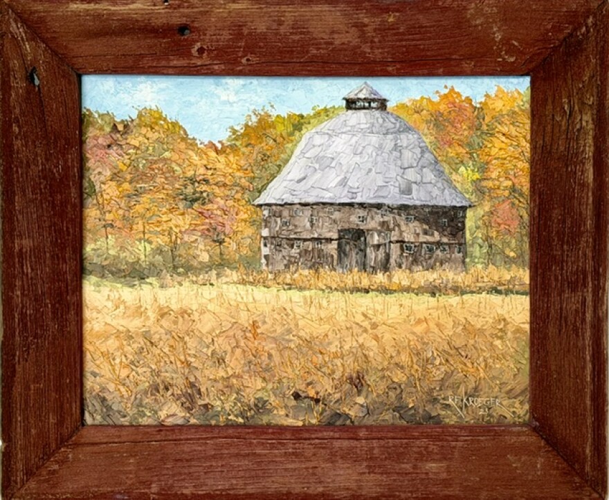 a round brown barn in field of gold in barn wood frame