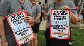 Union members hold protest signs outside school board.