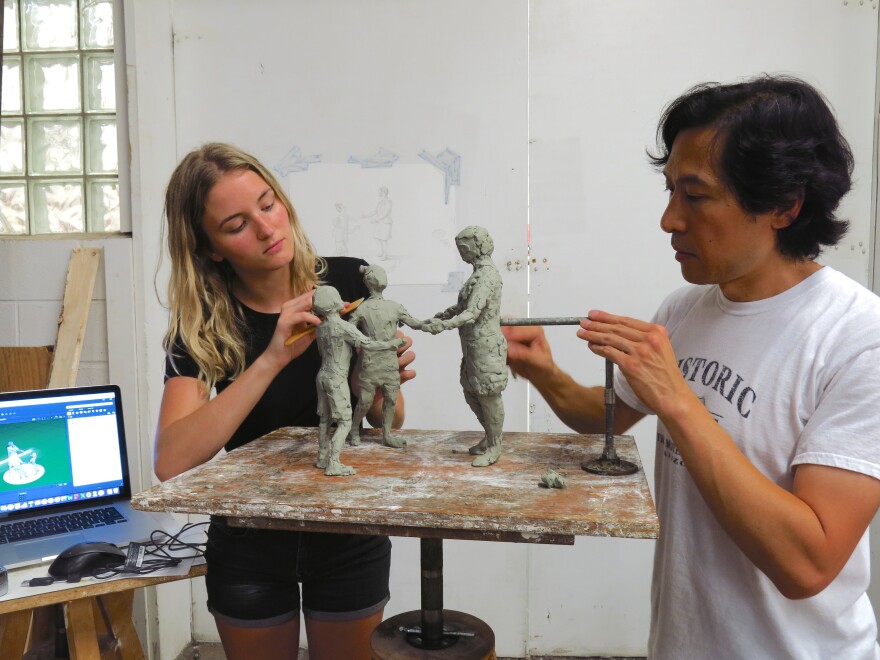 Artist Tom Tsuchiya (right) and apprentice Gina Erardi work on a clay model of the Marian Spencer statue.