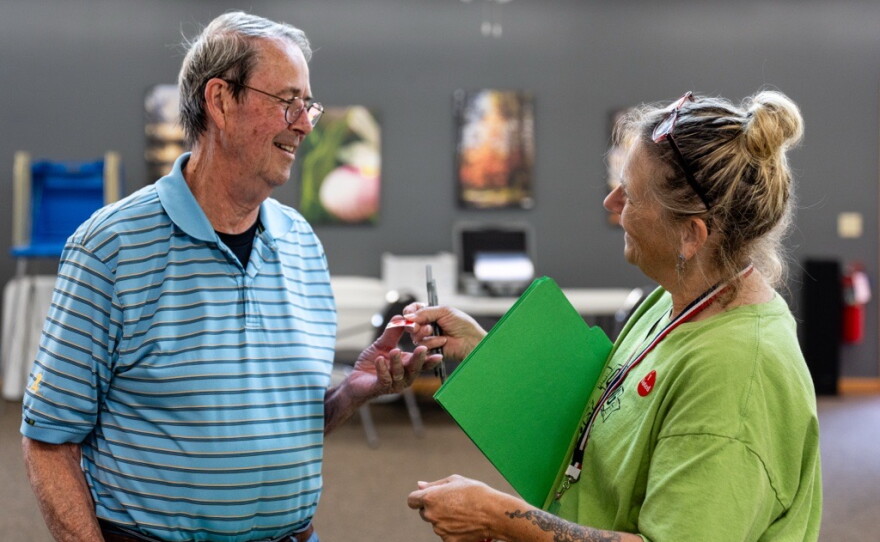 Dave Tanner takes an "I Voted" sticker from election judge Cathy Dietrich at Woodrow Town Hall on Primary Election Day, Aug. 11, 2026.