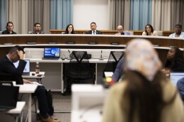 People sitting on a podium, listening to a speaker. 