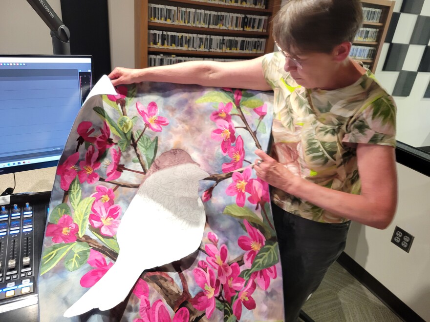 A person holding a piece of colorful fabric art