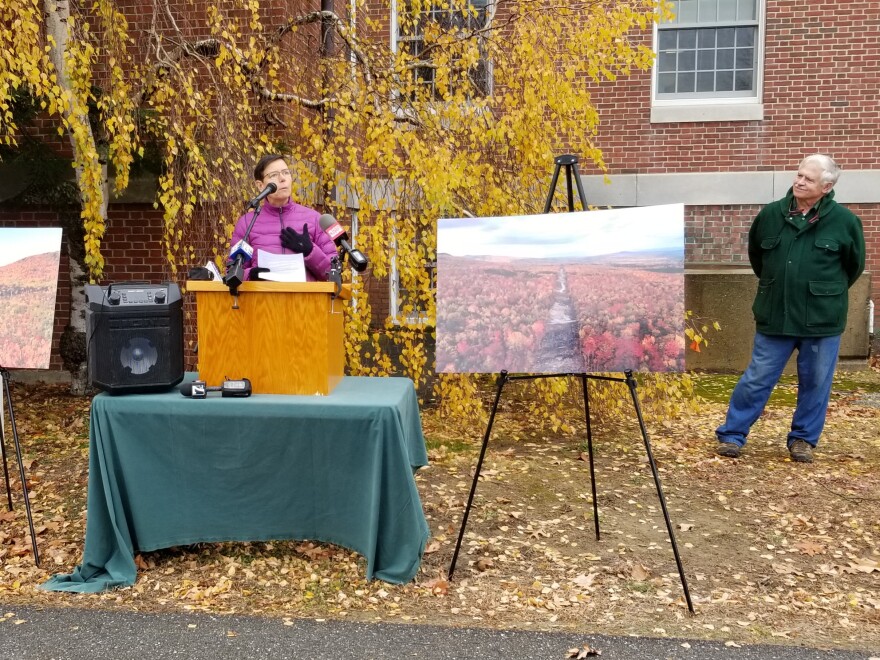 Eliza Townsend, Maine conservation policy director for the Appalachian Mountain Club, speaks at a rally calling on state environmental regulators to suspend the permit to build the New England Clean Energy Connect corridor. Tom Saviello, a former state lawmaker who helped lead the successful Question 1 campaign to block the corridor, watches from the side.