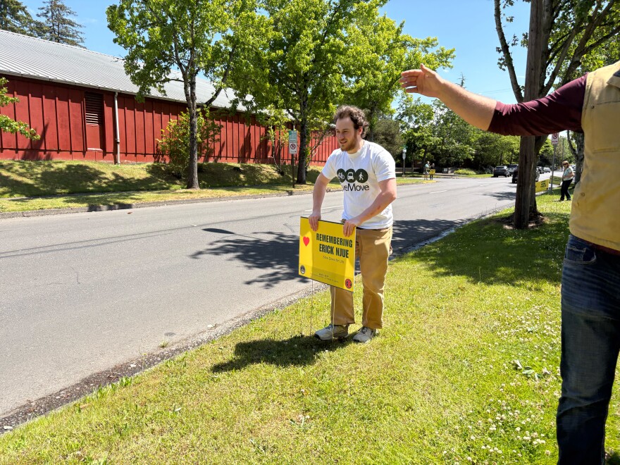 A student with Live Move plants a sign saying, "Remembering Erick Njue" on May 27, 2026.