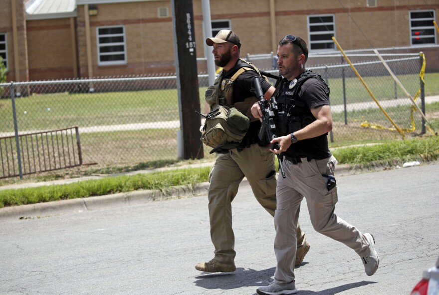 Police walk near Robb Elementary School following a shooting.