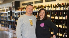 Adam and Susan Fleischer in front of a display of wine.