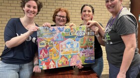 The speed jigsaw puzzlers, from left to right, Eleanor Candee, Christine Mills, Alex Babcock, and Valerie Mackie, hold up the puzzle they finished.