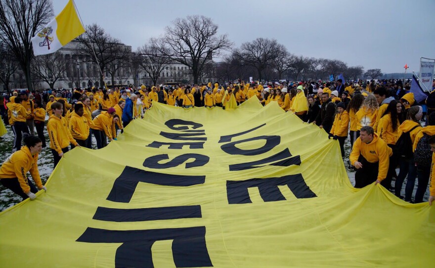 Anti-abortion rights activists hold a banner with the words Love Gives Life.