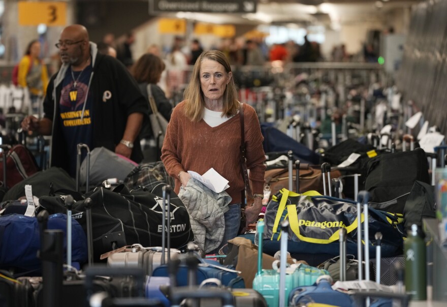 A traveler wades through the field of unclaimed bags at the Southwest Airlines luggage carousels at Denver International Airport, Tuesday, Dec. 27, 2022, in Denver. (AP Photo/David Zalubowski)