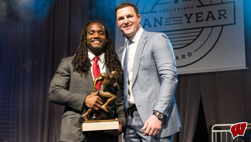 Young man accepts an award and poses next to a another man on stage