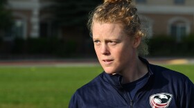 A woman in a "USA Rugby" jacket looks into the distance.