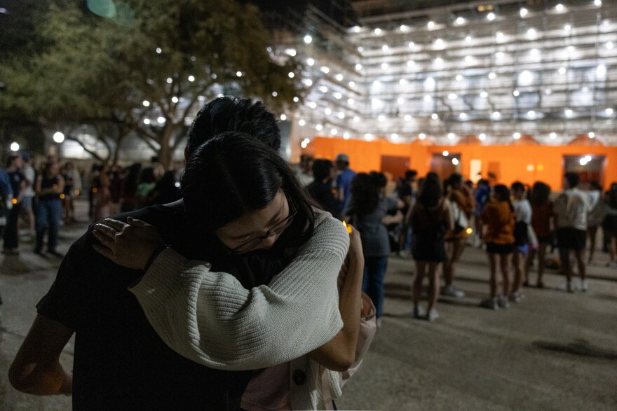 Emma Zuo, right, hugs Orion Ha, during a candlelight vigil on the University of Texas campus