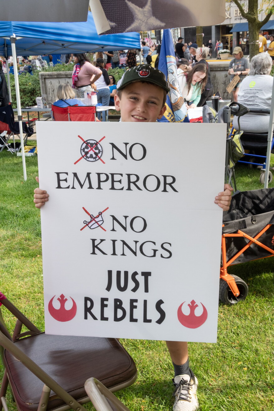 A young protestor holds up a sign at an earlier No Kings event. This week's event will focus on voter participation.