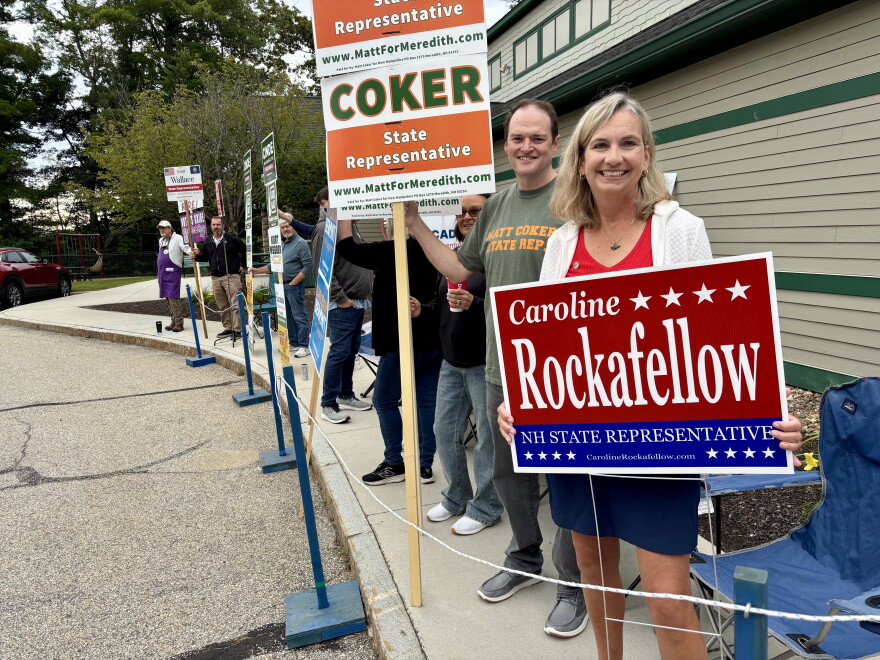 A candidate for the State House holds up a sign at the polls in Meredith. 