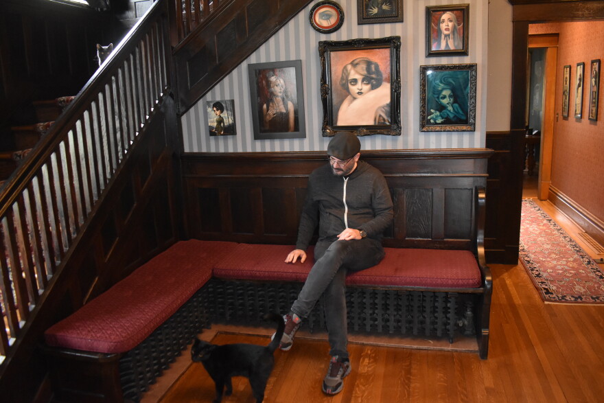 Rick Blanco sits with his cats Bela (near his feet) and Boris (on the stairs) in his historic Moss Ave. home in Peoria. Blanco said it costs a tenth of what he'd pay for a similar house in Los Angeles.