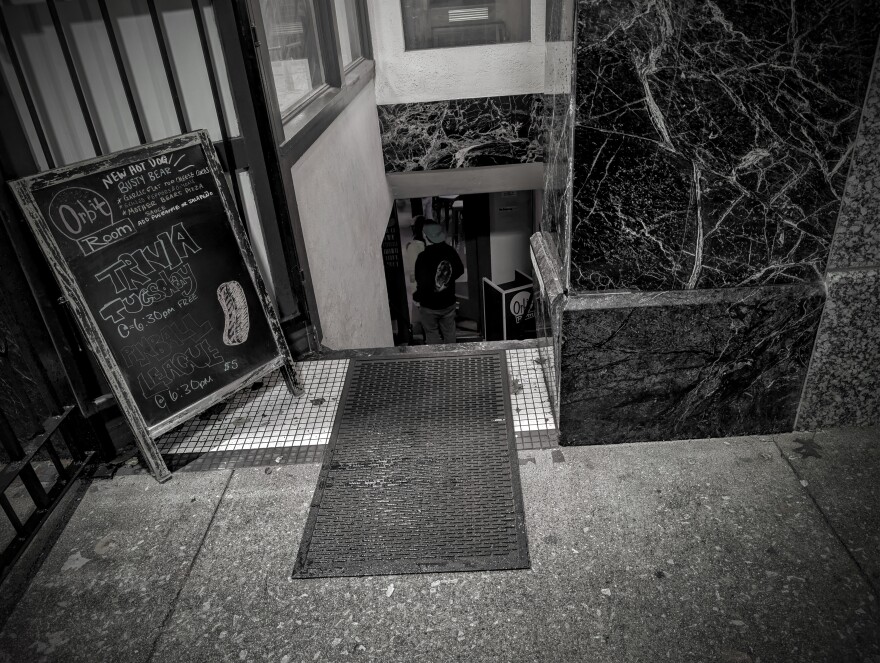 The outside of a bar and performance venue with a sandwich board out front that read "Orbit Room"