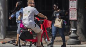A visitor pedals a bike powered by both pedals and battery-driven small motors in downtown Washington, Friday, Aug. 30, 2019. 