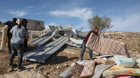Palestinian men gather their furniture and belongings after an Israeli bulldozer demolished their shack.
