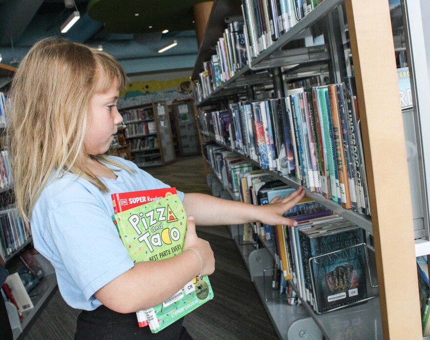 Elizabeth Etheridge, 6, looks through books at the Wichita downtown library on Monday. Federal cuts to the Institute of Museum and Library Services could impact Kansas summer reading programs.