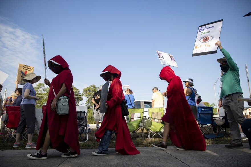People dressed as characters from author Margaret Atwood's "The Handmaid's Tale," were among the thousands who came to U.S. 41 and Daniels Parkway in Fort Myers Saturday for the third No Kings protest rally. Similar events were held in various Southwest Florida sites, other parts of the state and across the United States and the world.