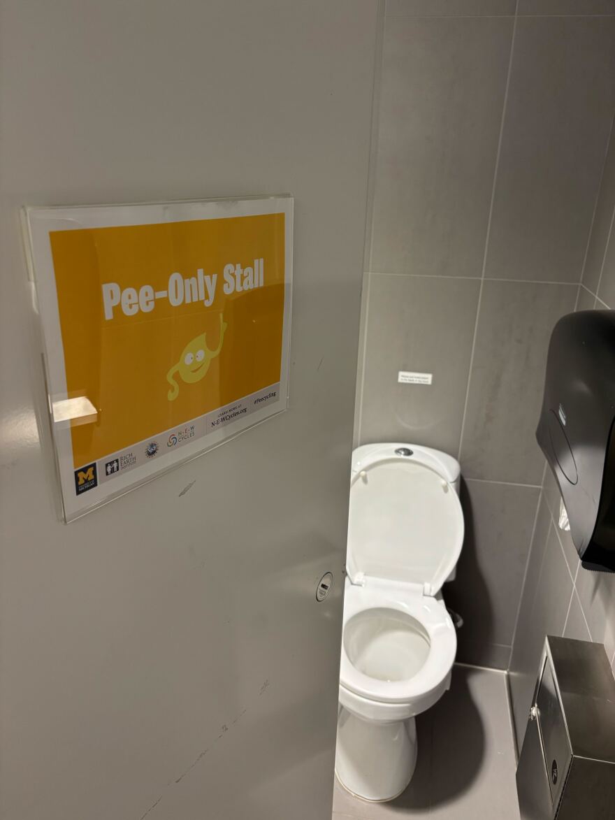 A yellow sign reading "Pee only stall" in front of a toilet.