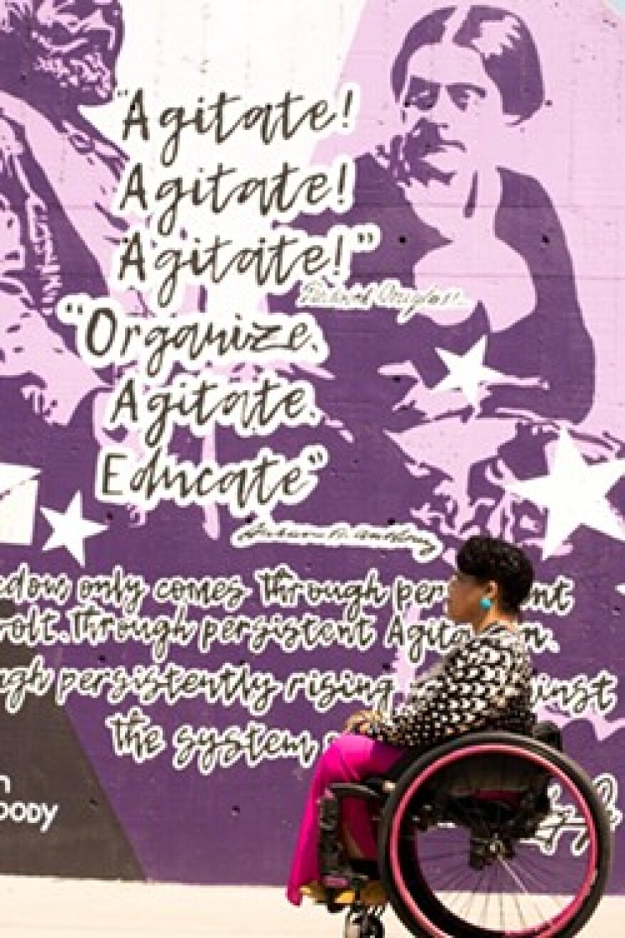 Luticha Doucette poses in front of a Susan B. Anthony mural in Rochester.