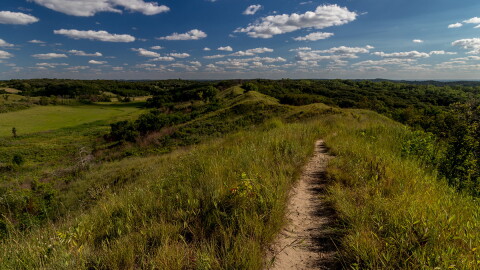 The Loess Hills are shown with green grass and a blue sky.
