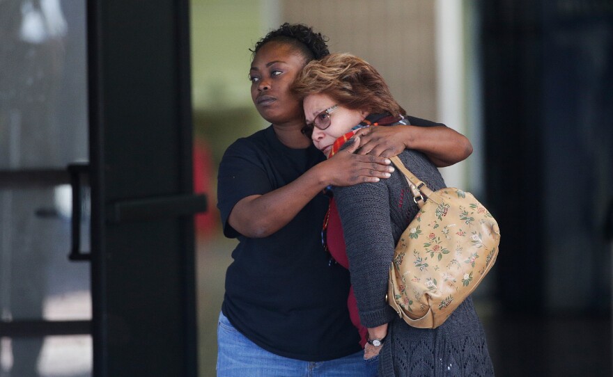 Two women embrace at a community center where family members gathered to pick up survivors after the shooting.