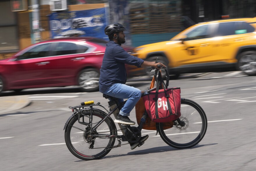 A person rides an e-bike through a busy intersection.