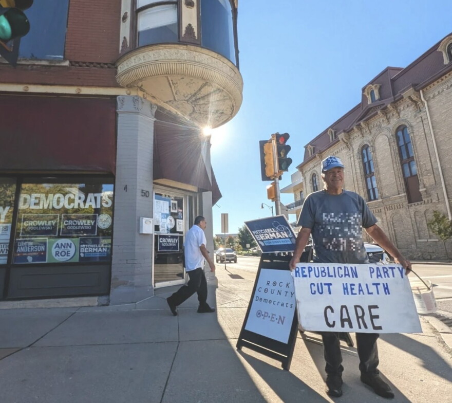 Dominic Vittone of Janesville holds a sign decrying Republican cuts to health care on the sidewalk outside the Rock County Democrats’ office in downtown Janesville from September of this year. Early voter data suggests southern Wisconsin could be a battleground area in deciding many races in the state. Midterm Election Day is Tuesday, Nov. 3.