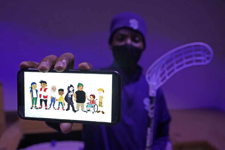 Seattle artist RC Johnson shows an image on his phone of characters he created for a floor hockey curriculum developed by the new Seattle Kraken NHL hockey team that can be used to teach hockey skills to elementary-aged students.