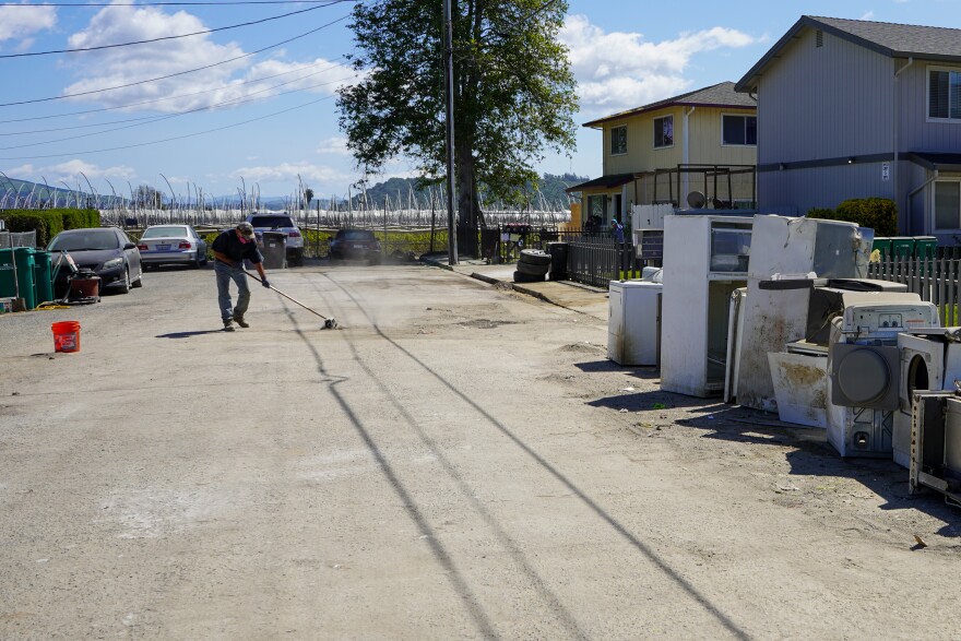 A Pajaro resident cleans up his street after floods in March 2023 devastated the community.