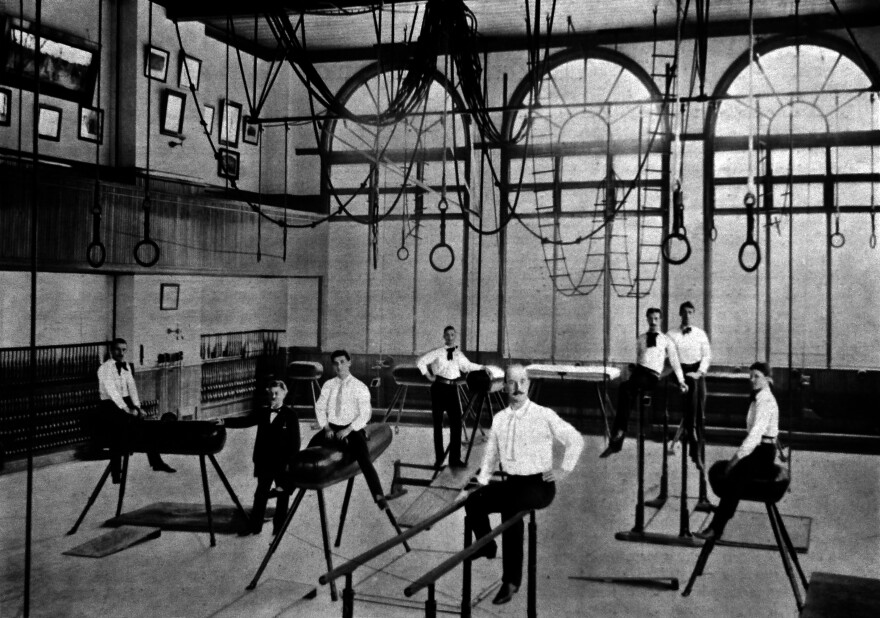 Turner Hall members sit on gymnastics equipment with ropes and swings overhead