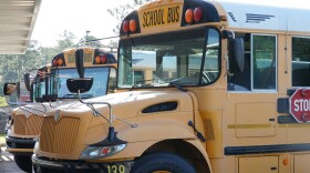 Three School buses parked next to each other in front of a building.