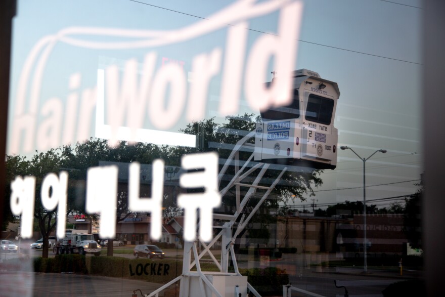 An image of the Dallas Police watchtower is reflected in the window of Hair World salon. 