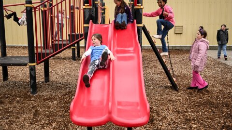 St. John Elementary student Melody Nelson, left, takes a turn on the slide with friends Cora Dennis, Mia Moseby and Charlotte Ward on Friday in St. John, Wash. The St. John School District is seeking voters to approve replacement levies, and their capital levy would help improve the minimalist playground.
