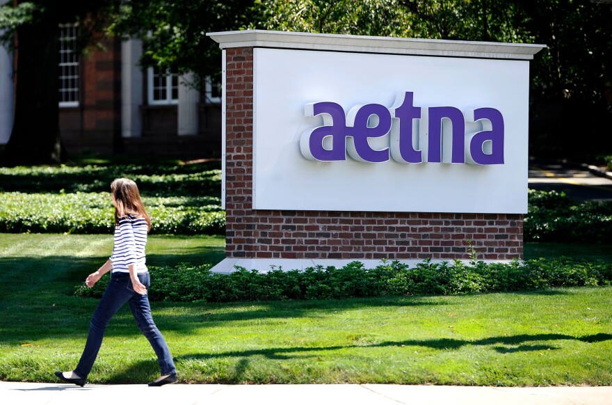 In this Tuesday, Aug. 19, 2014 file photo, apedestrian walks past a sign for health insurer Aetna Inc., at the company headquarters in Hartford, Conn.