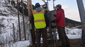 two people install a system near a pole outside
