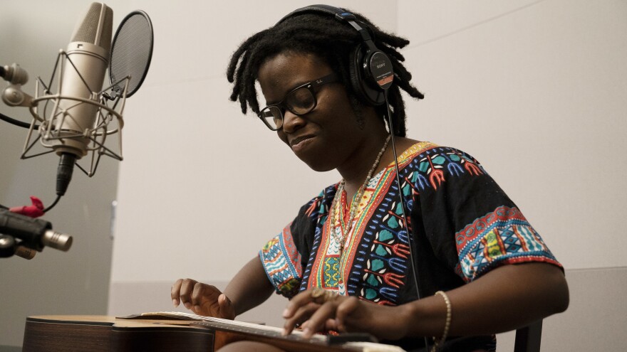 Tiny Desk Contest standout Yasmin Williams from Woodbridge, Va., lays a guitar face up, taps on the frets and plays percussion in the NPR studio.