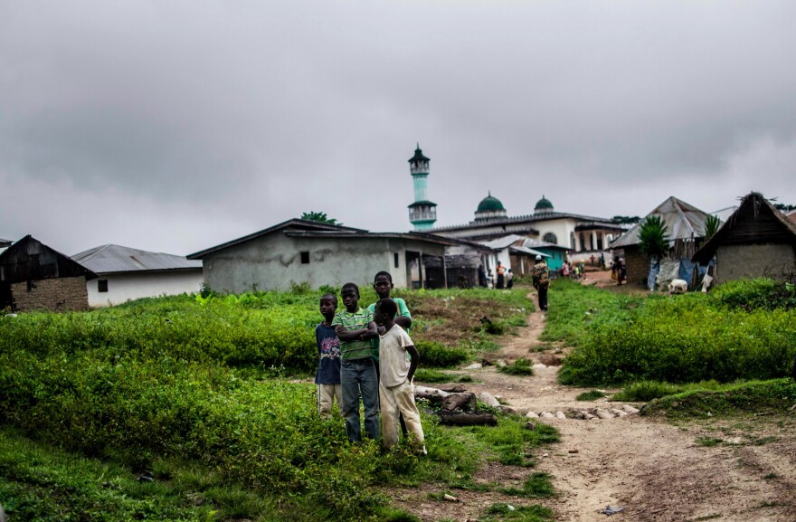 Children watch as a burial team returns to the town of Barkedu after interring a body.