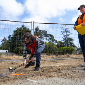 Cal Poly Humboldt geology students conduct a “tap test” using a sledgehammer to create ground vibrations that travel through the buried fiber-optic cable beneath. The vibrations are captured by a nearby seismometer-like sensor.