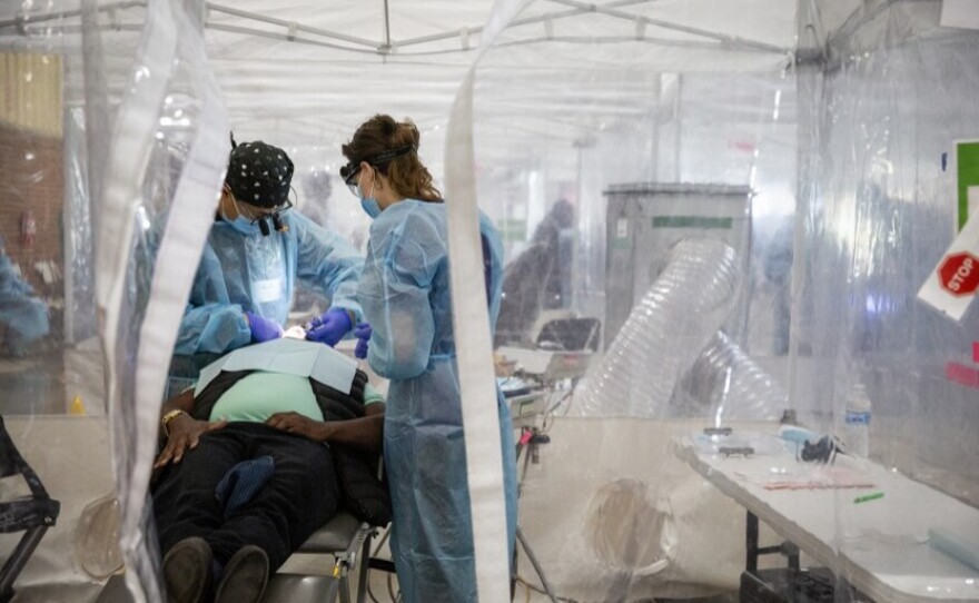 Volunteers treating a patient in a dental tent at the RAM clinic.