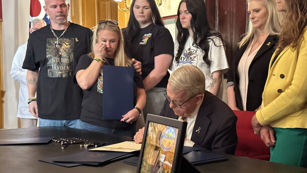 Gov. Mike DeWine signs an order recognizing National Childhood Cancer Awareness Month, with the Zurlinden family to his left.