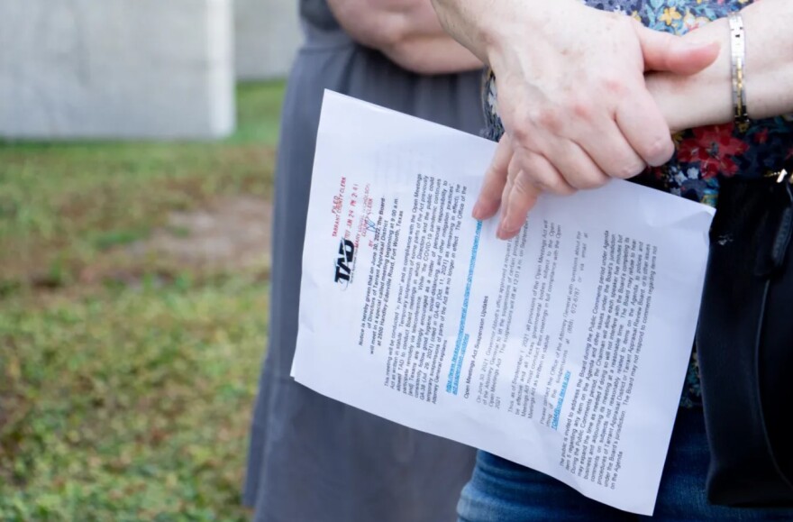 A person holds a piece of paper with a header that reads "TAD," for Tarrant Appraisal District.