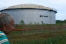 A woman walks near of a oil storage tank of Venezuela's state-run oil company, PDVSA