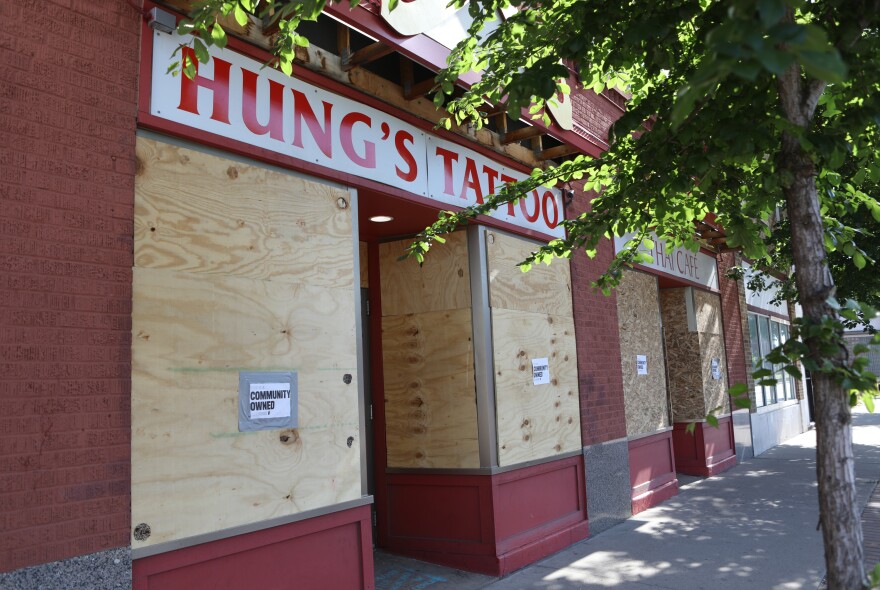 Boarded-up businesses bear signs that read "Community Owned" in the Frogtown neighborhood of St. Paul, Minn.