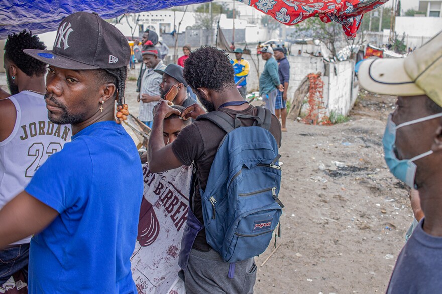 Migrants set up a temporary barber shop across the street from the Senda De Vida migrant shelter in Reynosa on Sunday, when the facility offers a weekly church service.